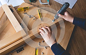 Woman assembly wooden furniture,fixing or repairing house with screwdriver tool.modern living concepts