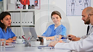 Woman assistent typing on laptop at desk looking at camera