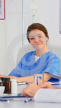Woman assistent typing on laptop at desk looking at camera