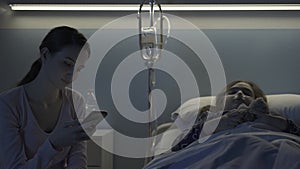 Woman assisting her daughter at the hospital and using her phone