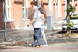 Woman Assisting Her Father While Crossing Road