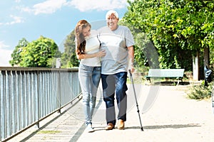 Woman Assisting Her Father While Walking In Park