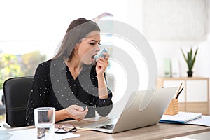 Woman with asthma inhaler at table