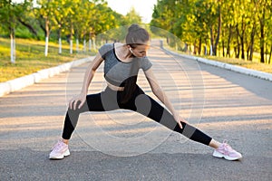 Woman athlet in black sportswear doing stretching exercises outdoor