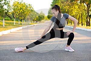 Woman athlet in black sportswear doing stretching exercises in the park