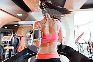 Woman athlete with balnk screen smartphone running on treadmill