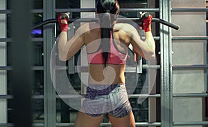 Woman athlete doing pull ups on the horizontal bar