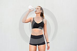 Woman, athlete and drinking water in studio, thirsty and hydrate after workout on white background. Female person, detox