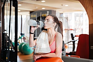 Woman athlete drinking water on training in gym