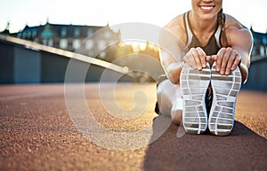 Woman athlete grabs her shoes as she stretches