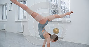 Woman athlete performs callisthenics exercises with gymnastic ball on white background, sport exercises isolated