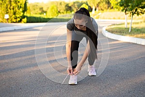 Woman athlete runner tie her shoelaces in the summer before run.