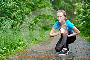 Woman athlete runner touching Knee in pain, fitness woman running in summer park. Healthy lifestyle and sport concept