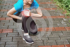 Woman athlete runner touching Knee in pain, fitness woman running in summer park. Healthy lifestyle and sport concept