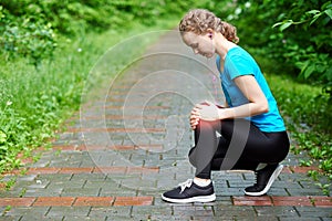 Woman athlete runner touching Knee in pain, fitness woman running in summer park. Healthy lifestyle and sport concept