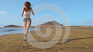 Woman athlete silhouette running on beach sprinting waves crashing on seaside morning background slow motion