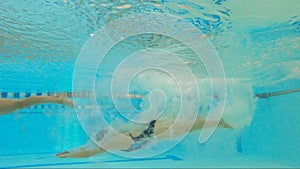 Woman athlete swims underwater in the pool.