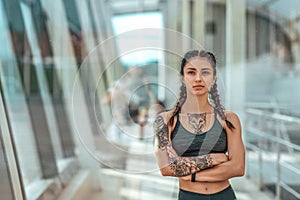 Woman athlete tattoos, summer city, resting after workout fitness. Sportswear top. Concept of strength, femininity