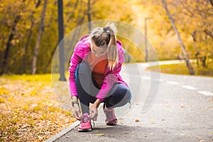 Woman athlete tying shoelaces on sneakers on the track