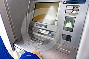 A woman at an ATM presses a button to withdraw cash