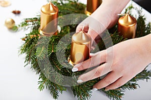 Woman attaches candle on a Christmas wreath