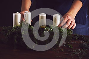 Woman attaches candle holder on a Christmas wreath