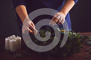Woman attaches candle holder on a Christmas wreath