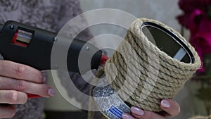 A woman attaches a rope to a tin can with a glue gun. Crafts in self-isolation. Close-up shot