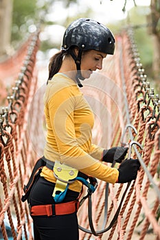 Woman attaching carabiner to rope bridge