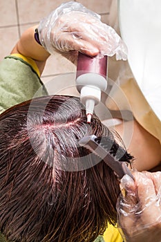 Woman attempting to apply chemical hair color onto scalp