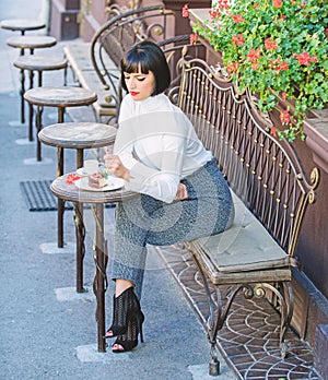 Woman attractive brunette eat gourmet cake cafe terrace background. Gastronomical enjoyment. Girl relax cafe with cake