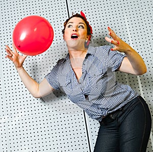 Woman attractive joyful senior woman playing with red balloon inside her apartment just near fireplace