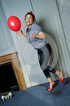 Woman attractive joyful senior woman playing with red balloon inside her apartment just near fireplace