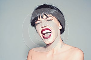 Woman with attractive red lips looks at camera. Girl on scandalous shouting face posing with naked shoulders. Lady in photo