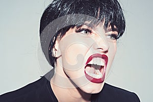 Woman with attractive red lips shouting, close up. Angry boss concept. Girl on scandalous shouting face wears formal photo