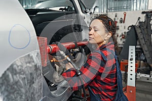 Woman auto mechanic fixing car in automobile garage