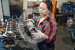 Woman auto mechanic fixing car engine in garage