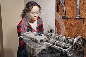 Woman auto mechanic fixing car engine at service station