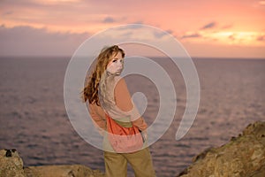 Woman in autumn fashion dress on the ocean coast, on rocky beach.