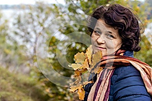 Woman in the autumn forest with a happy look holds an oak branch in her hand. A walk in the woods