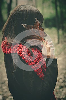 Woman with autumn leaf hide face outdoor