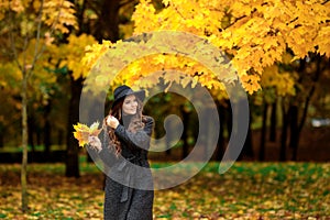 Woman with autumn leaves in hand and fall yellow maple garden background