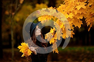 Woman with autumn leaves in hand and fall yellow maple garden background