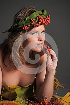 woman in autumn leaves and a wreath of mountain ash