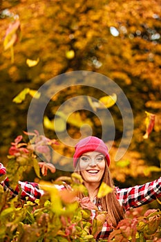 Woman in autumn park throwing leaves up in the air