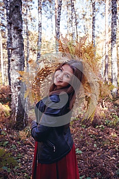 Woman autumn portrait. cute girl outdoors with a bouquet of yellow fern in the forest, autumn fall concept.