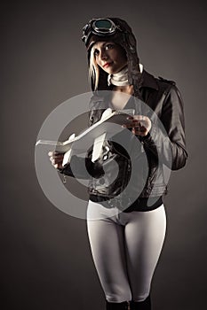 woman in aviator hat standing with toy airplane in hand