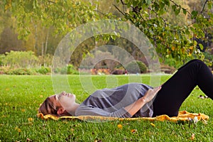 Woman awaiting for a baby, cute pregnant female lying down on fresh green grass in the garden, sunny day, happy and healthy pregna