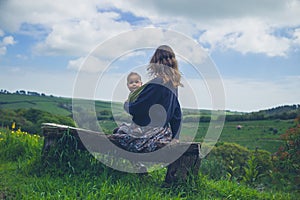 Woman with baby on bench in nature