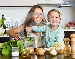 Woman with baby cooking at kitchen